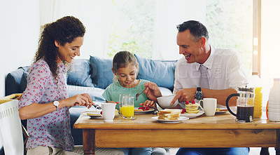 Buy stock photo Shot of a cute little girl having breakfast with her parents in the morning at home