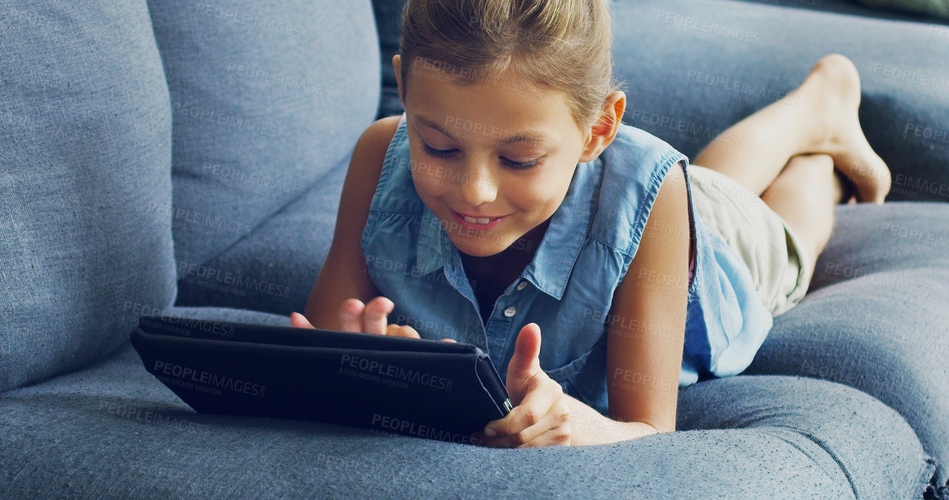 Buy stock photo Shot of a cute little girl using a digital tablet on the sofa at home