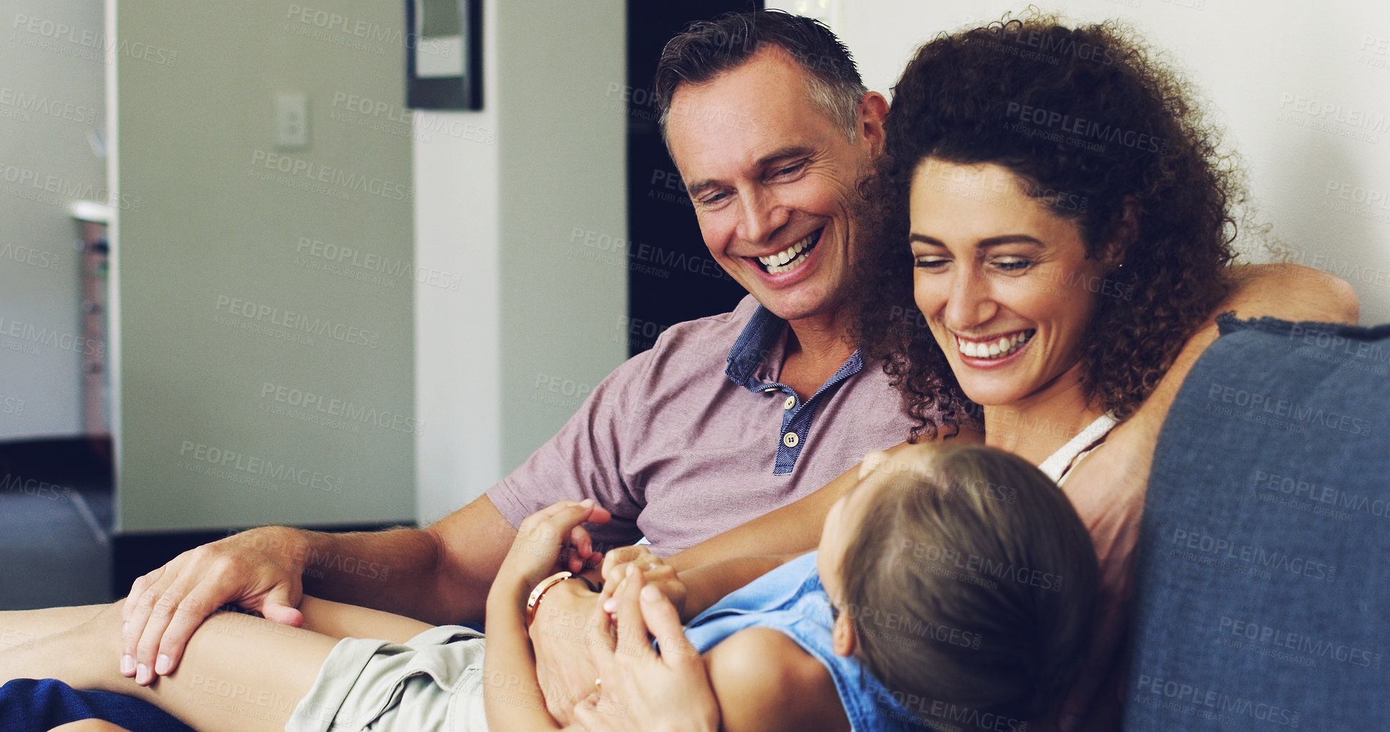 Buy stock photo Shot of a cute little girl relaxing with her mother and father on the sofa at home