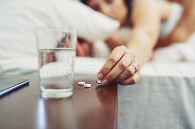 Buy stock photo Shot of an unrecognizable woman lying in bed and taking a pill to drink after waking up sleeping in bed