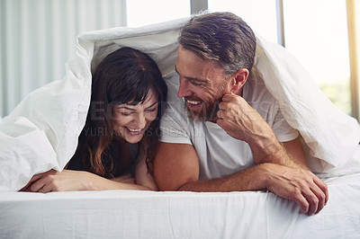 Buy stock photo Cover, laugh and happy couple in bed for calm morning bonding, comfort and love in home together. Smile, man and woman relax in bedroom with fun, romantic marriage and wake up on weekend in apartment