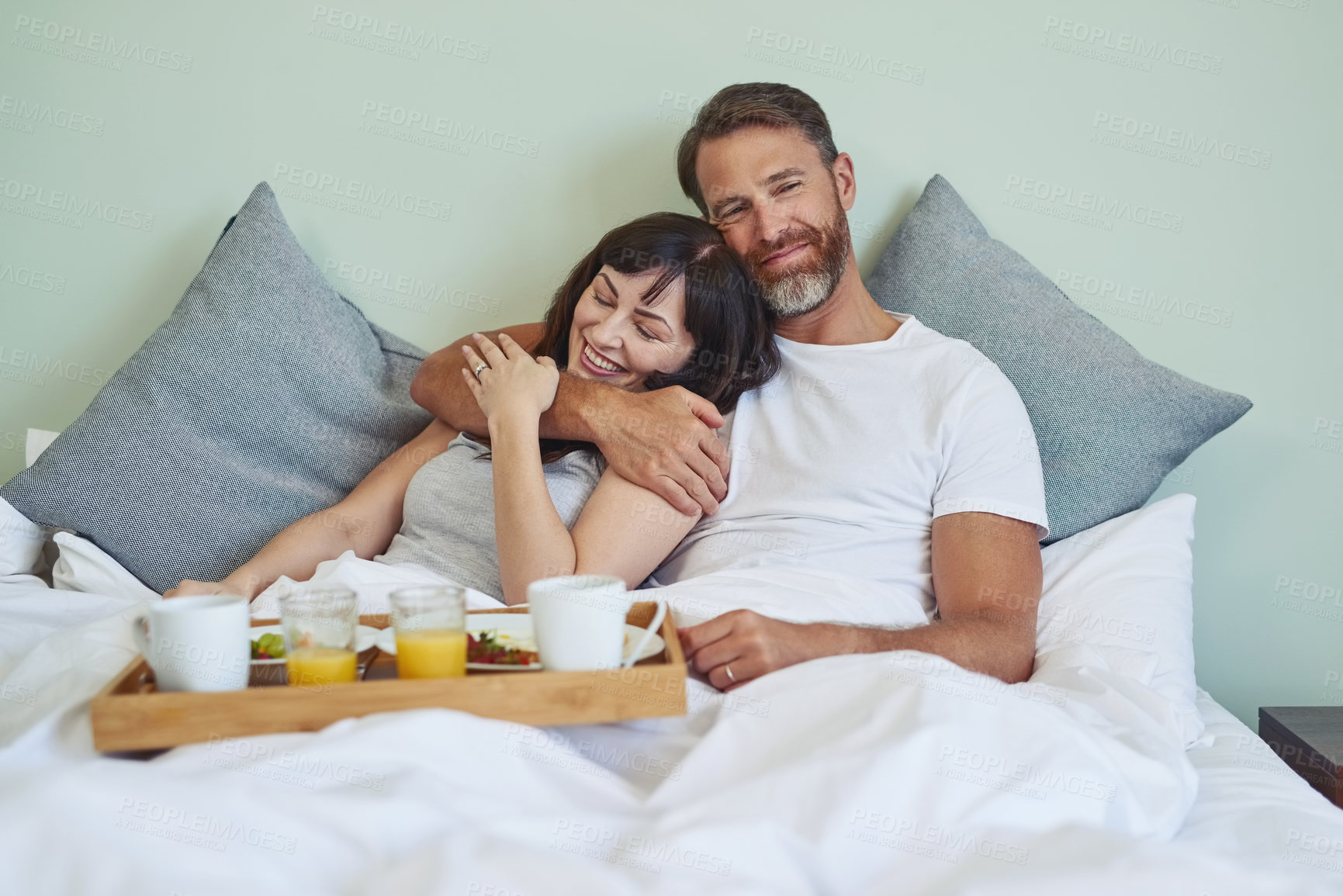 Buy stock photo Couple, relax and happy with hug in bedroom, bed and breakfast for rental on honeymoon vacation with love. Man, woman and together in morning with affection, bonding and commitment with care.