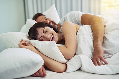Buy stock photo Shot of a relaxed young couple trying sleeping in each other's arms in bed during morning hours