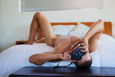Buy stock photo Shot of a handsome shirtless young man taking a picture on his bed at home