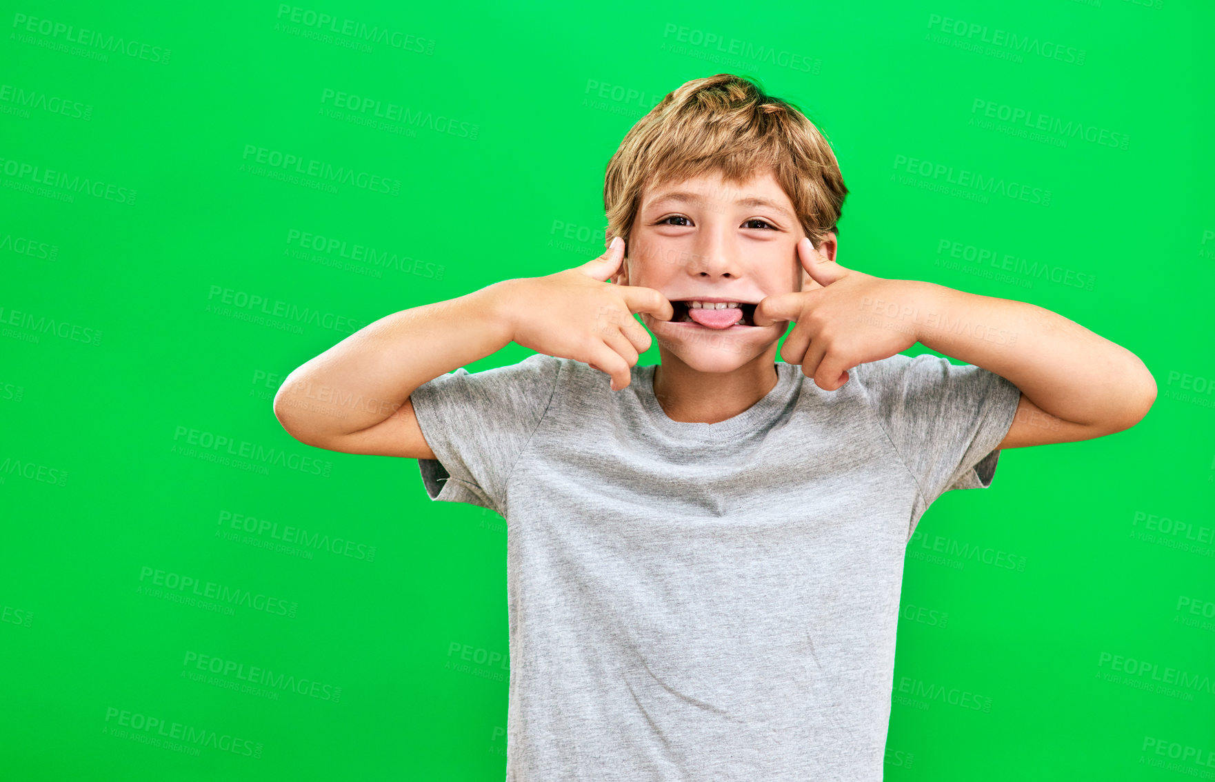 Buy stock photo Studio portrait of a young boy making a funny face against a green background