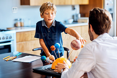 Buy stock photo Shot of a father helping his little son with a school project at home