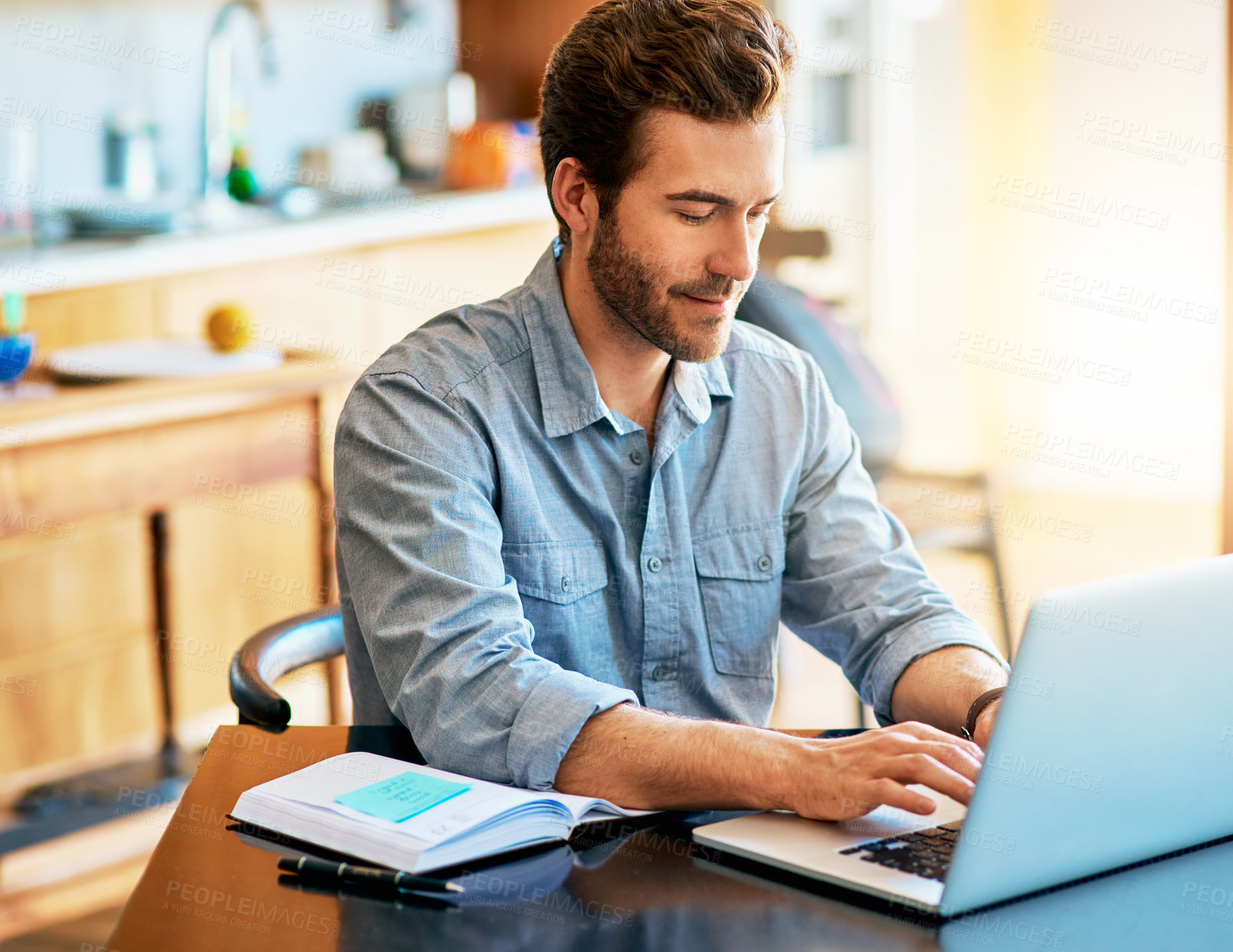 Buy stock photo Shot of a handsome young man working on a laptop at home