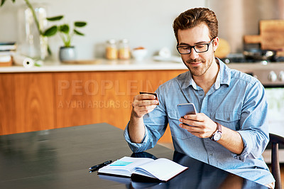 Buy stock photo Shot of a handsome young man using a cellphone and credit card at home