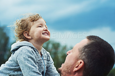Buy stock photo Shot of a cheerful little girl being picked up by her father outside during a cloudy day