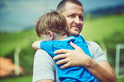 Buy stock photo Shot of a cheerful middle aged man holding his little boy in his arms outside during a cloudy day