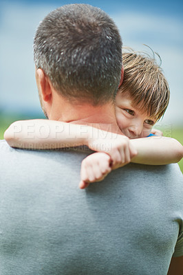 Buy stock photo Shot of a cheerful middle aged man holding his little boy in his arms outside during a cloudy day
