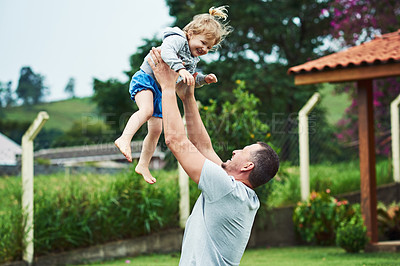 Buy stock photo Shot of a cheerful little girl being  lifted up in the air by her father outside during a cloudy day