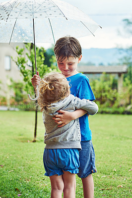 Buy stock photo Shot of a cheerful little boy and girl standing together under an umbrella outside during a rainy day