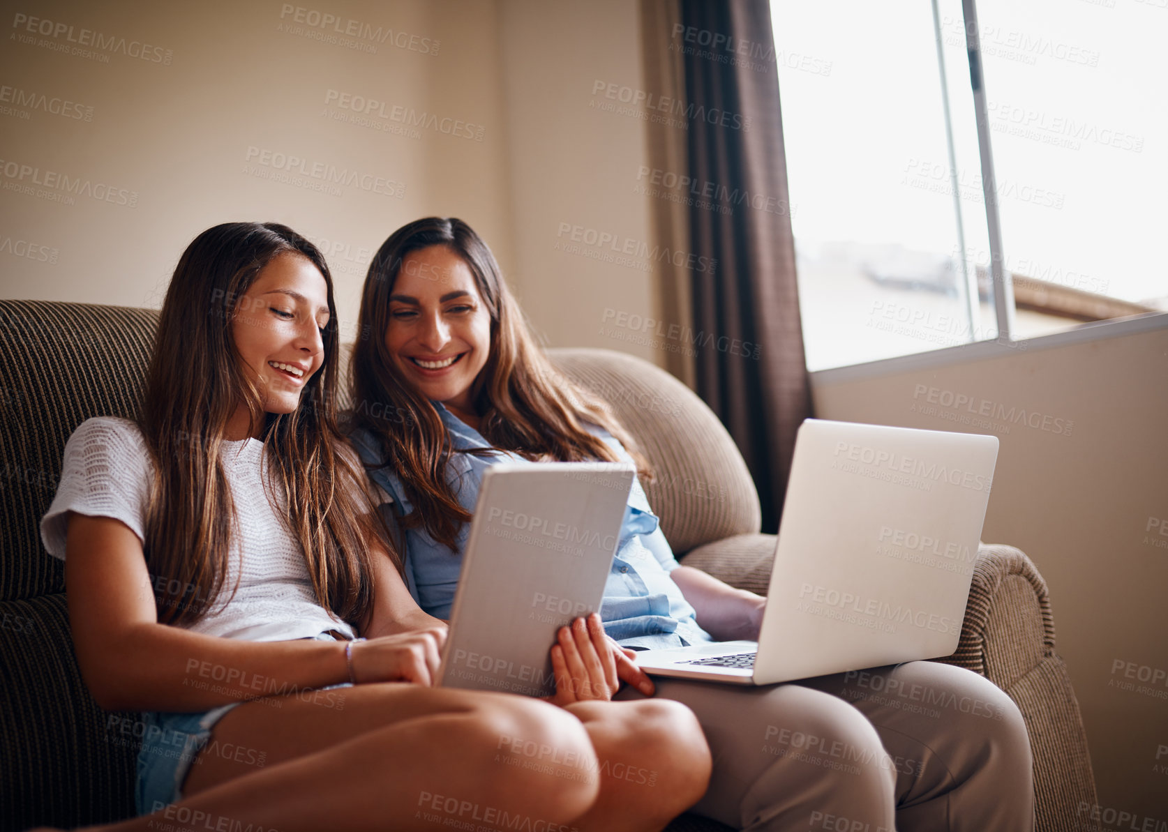 Buy stock photo Cropped shot of an attractive mother and her daughter using wireless technology while sitting on the sofa at home
