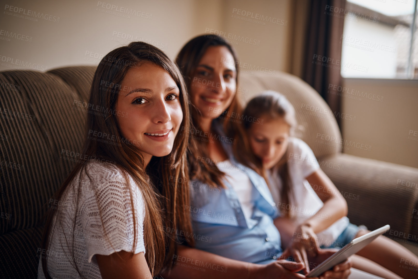 Buy stock photo Cropped portrait of an attractive mother watching movies on a tablet with her two daughters at home
