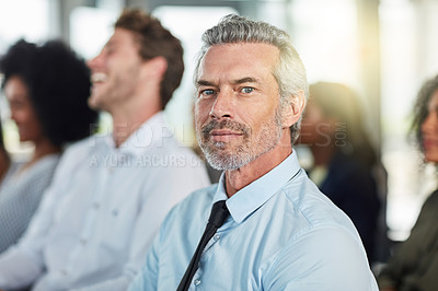 Buy stock photo Cropped portrait of a handsome mature businessman attending a seminar with his colleagues