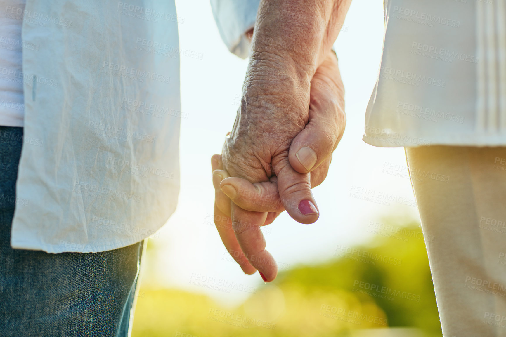 Buy stock photo Cropped shot of a senior couple holding hands in a park