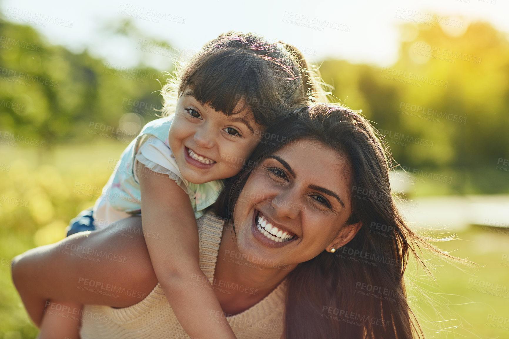 Buy stock photo Shot of an adorable little girl and her mother enjoying a piggyback ride in the park