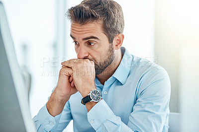 Buy stock photo Shot of a young businessman looking anxious while working on a computer in an office