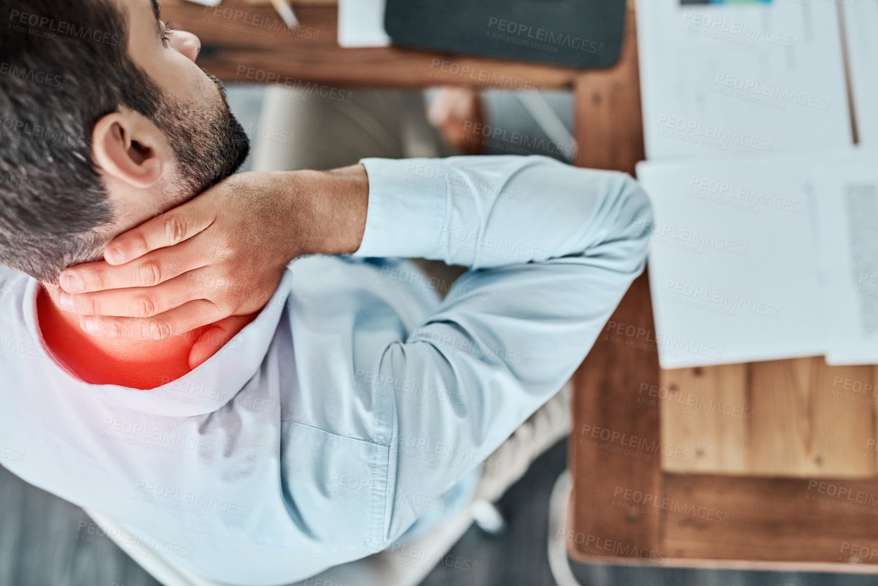 Buy stock photo High angle shot of a young businessman suffering with neck pain while working in an office