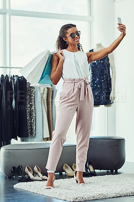 Buy stock photo Shot of an attractive young woman taking a selfie while on a shopping spree in a boutique