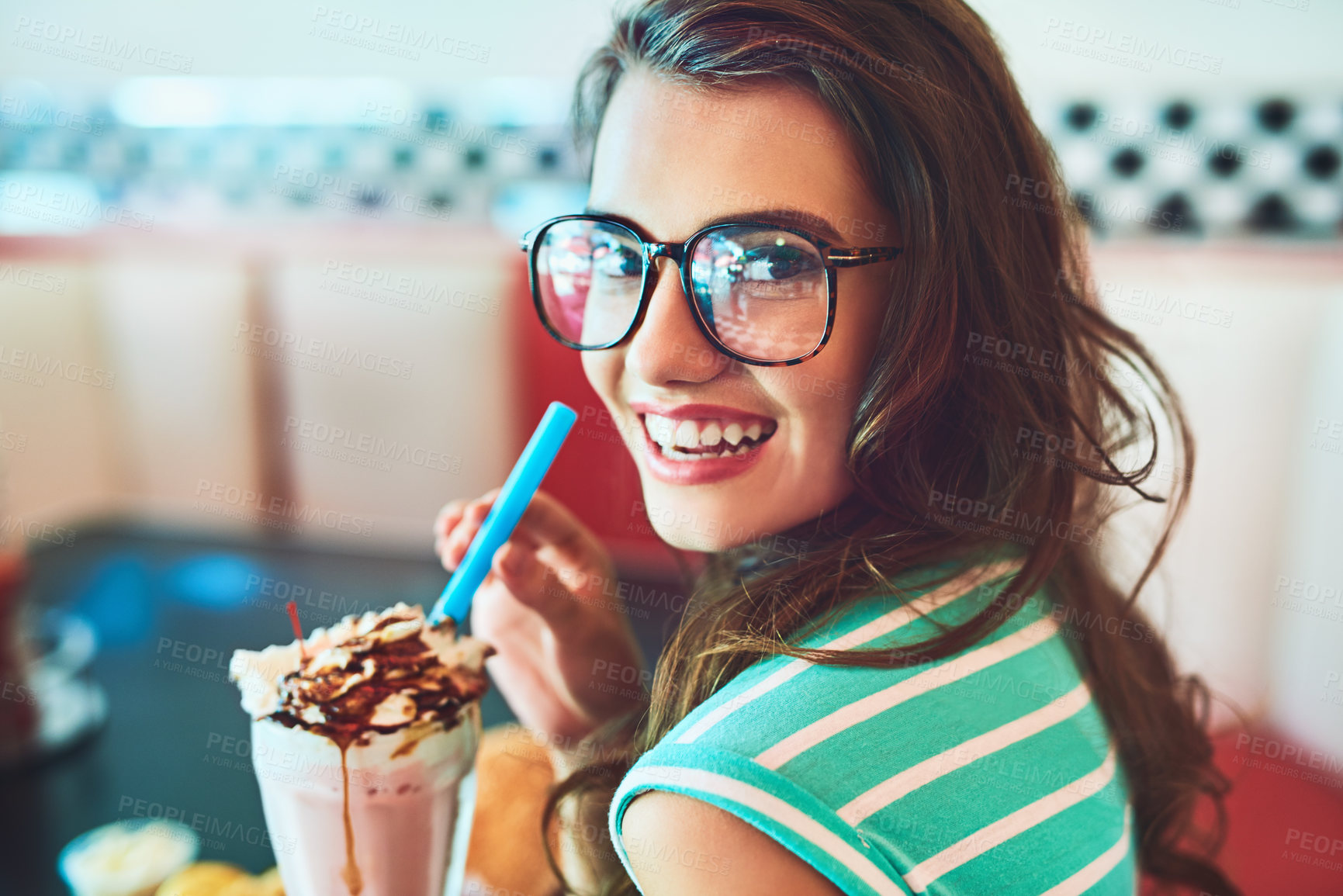 Buy stock photo Cropped portrait of an attractive young woman enjoying a milkshake in a retro diner