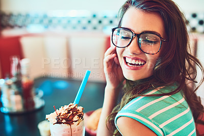 Buy stock photo Cropped shot of an attractive young woman enjoying a milkshake in a retro diner