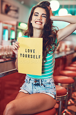 Buy stock photo Cropped portrait of an attractive young woman holding up a sign in a retro diner