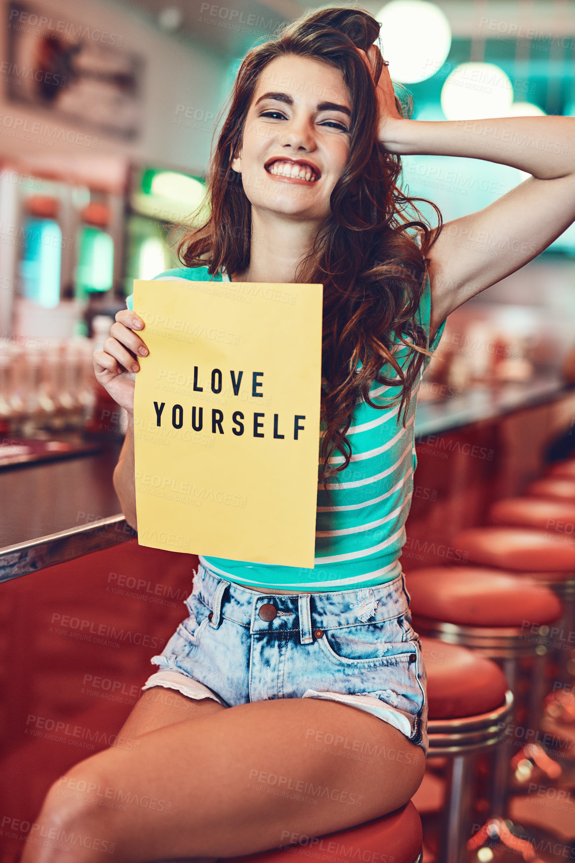 Buy stock photo Cropped portrait of an attractive young woman holding up a sign in a retro diner