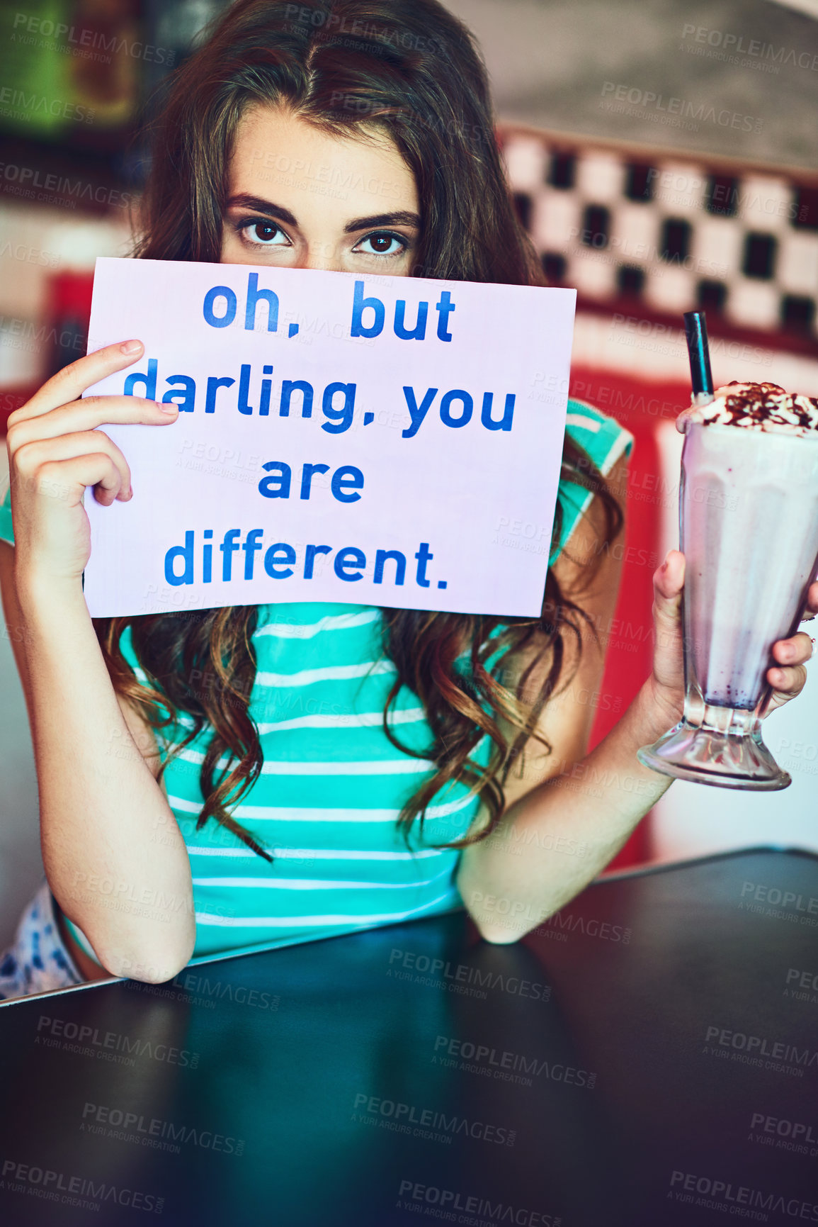 Buy stock photo Cropped portrait of an attractive young woman holding up a sign while enjoying a milkshake in a retro diner