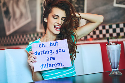 Buy stock photo Cropped shot of an attractive young woman holding up a sign while enjoying a milkshake in a retro diner