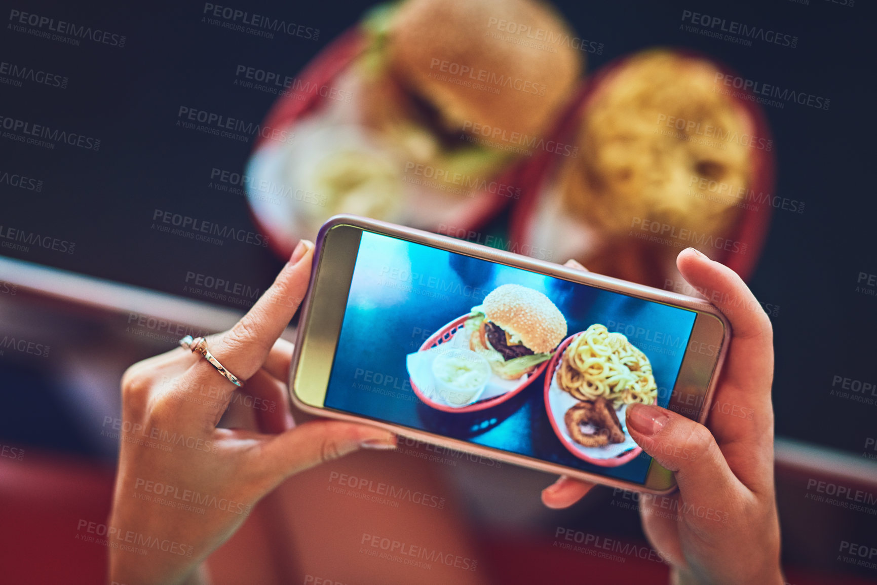 Buy stock photo High angle shot of an unrecognizable young woman taking photos of her burger in a retro diner