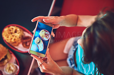 Buy stock photo High angle shot of an unrecognizable young woman taking photos of her burger in a retro diner