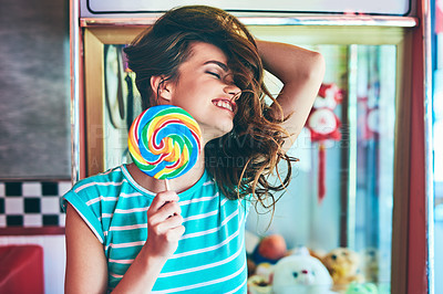 Buy stock photo Cropped shot of an attractive young woman eating a giant lollipop in a retro diner