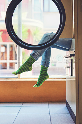 Buy stock photo Shot of an unrecognizable woman seated on a washing machine with her legs showing and showing her bright green striped socks inside of a laundry room