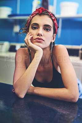 Buy stock photo Portrait of an attractive young woman resting her arms on a counter while waiting for her washing to wash inside of a laundry room