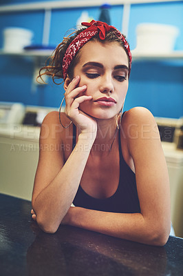 Buy stock photo Shot of an attractive young woman resting her arms on a counter while waiting for her washing to wash inside of a laundry room