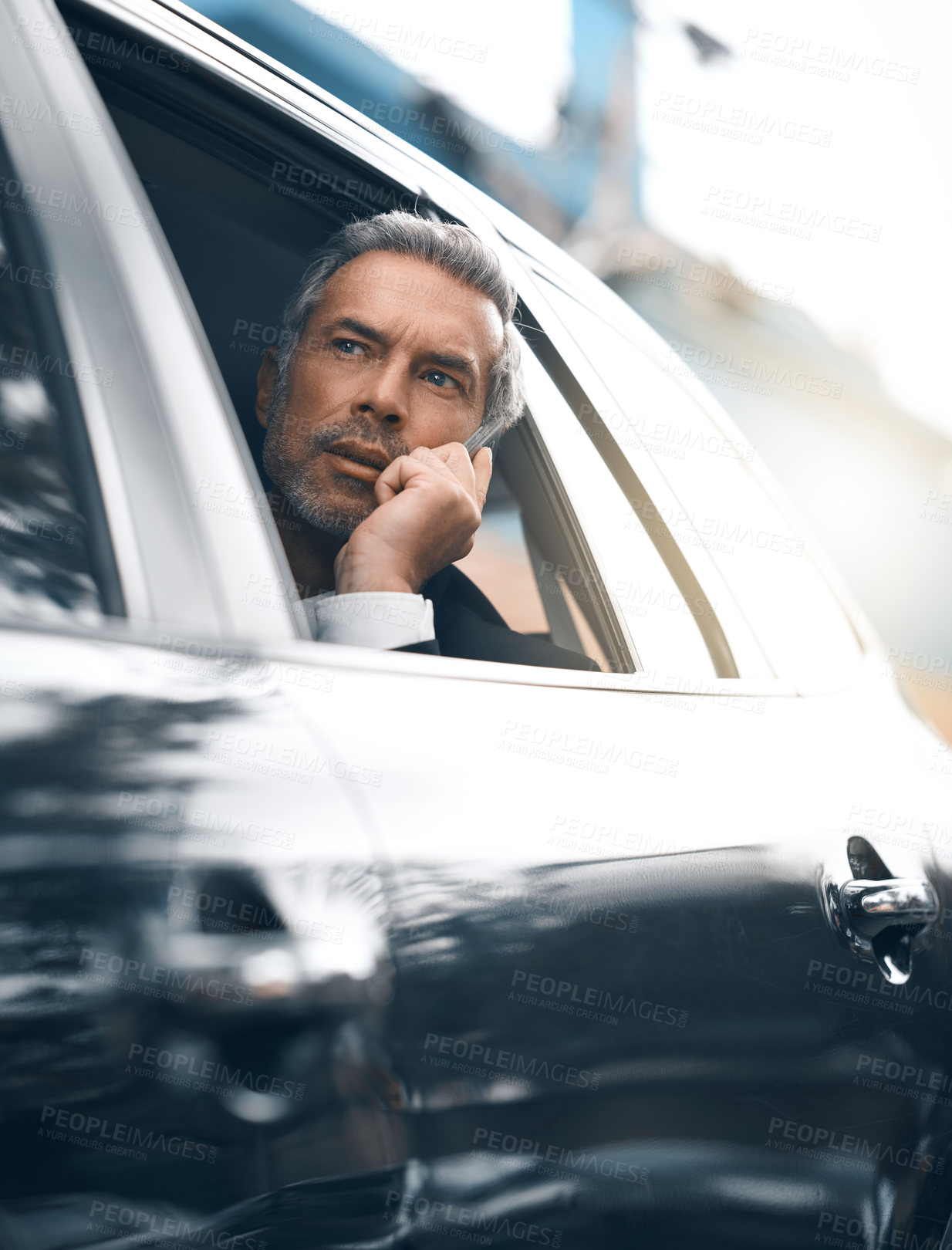 Buy stock photo Cropped shot of a handsome mature businessman making a call from the backseat of a car during his morning commute