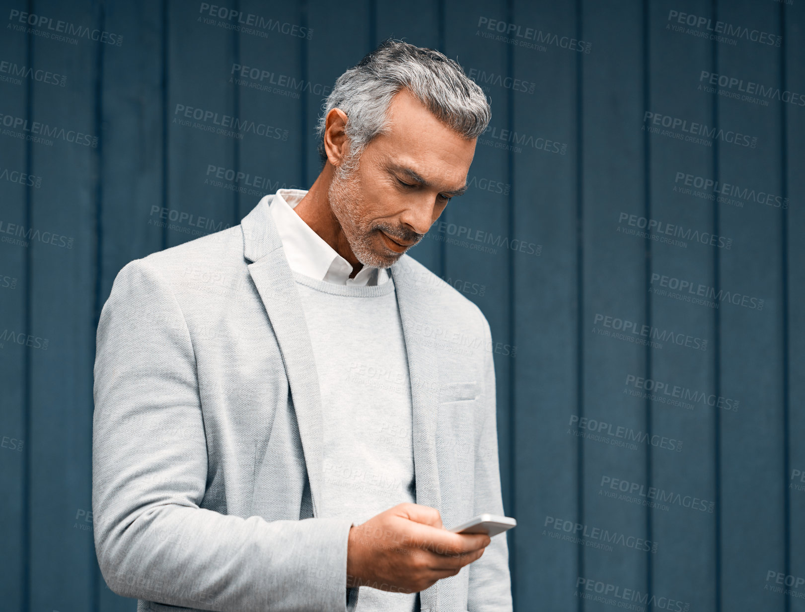 Buy stock photo Cropped shot of a smartly dressed mature businessman using a cellphone outside
