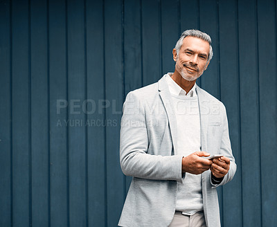 Buy stock photo Cropped shot of a smartly dressed mature businessman using a cellphone outside