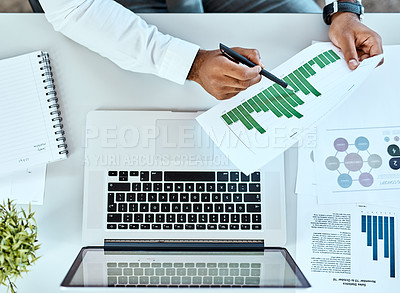 Buy stock photo High angle shot of an unrecognizable businessman going through paperwork while working on a laptop in an office