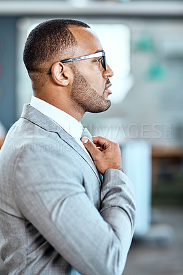 Buy stock photo Shot of a young businessman adjusting his tie in an office