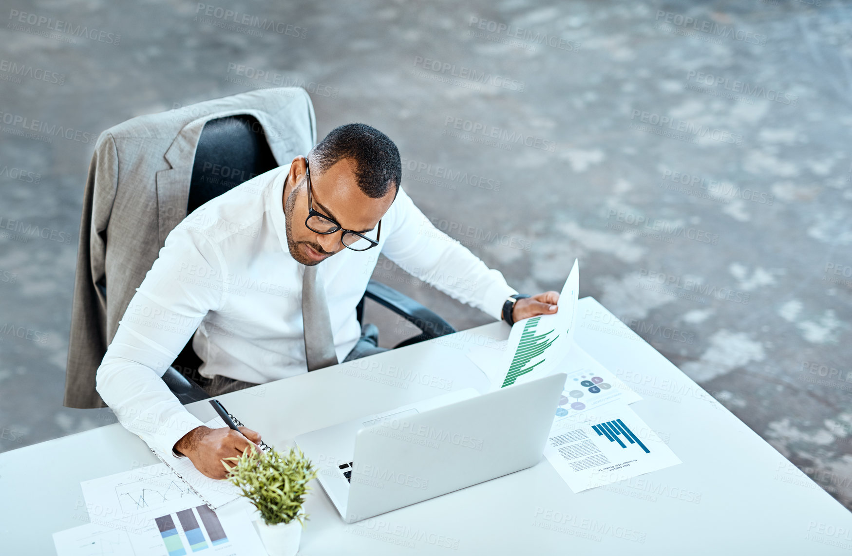 Buy stock photo Financial analyst, focus and black businessman writing in his office space or reading data report and employee on desk. Statistics, stock market and corporate worker with graphs  or laptop on mockup