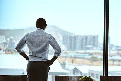 Buy stock photo Rearview shot of a businessman looking out the window in an office