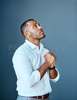 Buy stock photo Studio shot of a young businessman looking up with his hands clasped in prayer