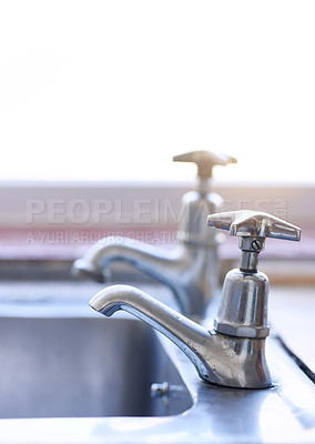 Buy stock photo Shot of two dripping taps waisting a little bit of water in a basin inside of a house during the day