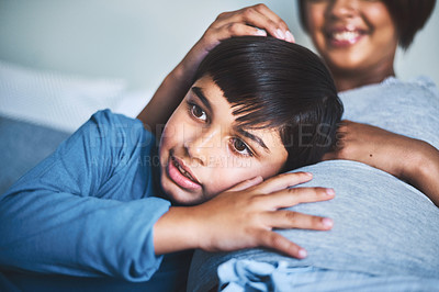 Buy stock photo Cropped shot of an adorable little boy lying on his mother's lap while trying to hear the baby