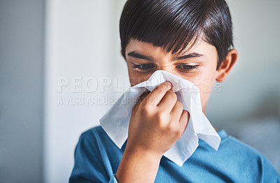 Buy stock photo Cropped shot of an adorable little boy blowing his nose while standing in his home