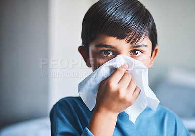 Buy stock photo Cropped portrait of an adorable little boy blowing his nose while standing in his home
