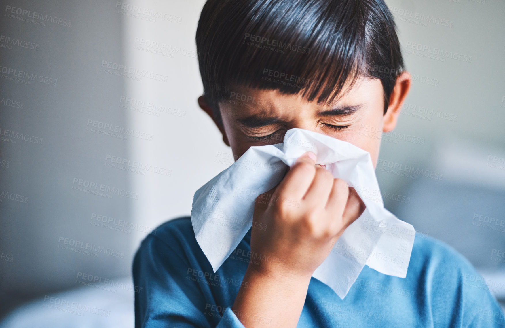 Buy stock photo Cropped shot of an adorable little boy blowing his nose while standing in his home
